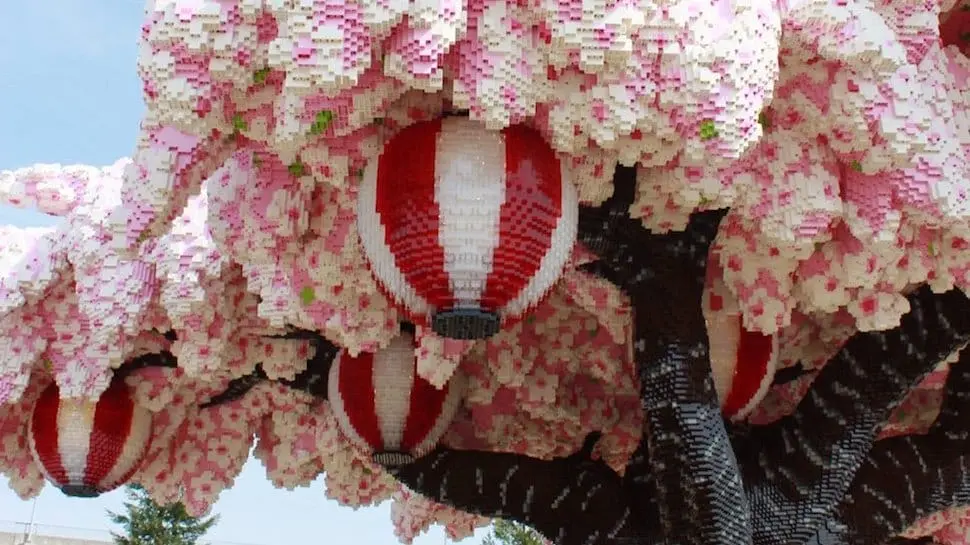 Close-up of the LEGO cherry blossom tree at LEGOLAND Japan showing pink and white sakura blossoms with hanging red and white lanterns built from LEGO bricks.
