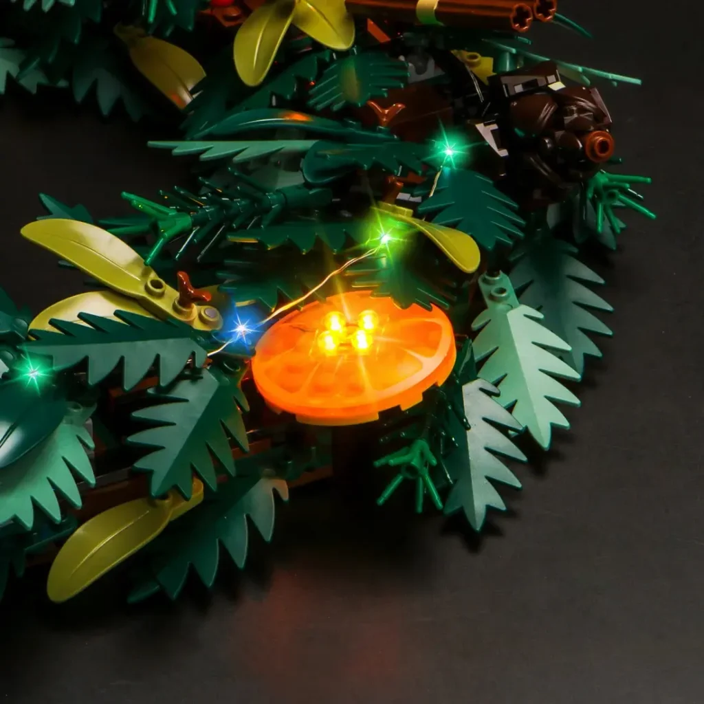 Close-up of the LEGO Icons Wreath 10340 with BrickBling light kit featuring illuminated orange slice details and glowing holiday greenery.
