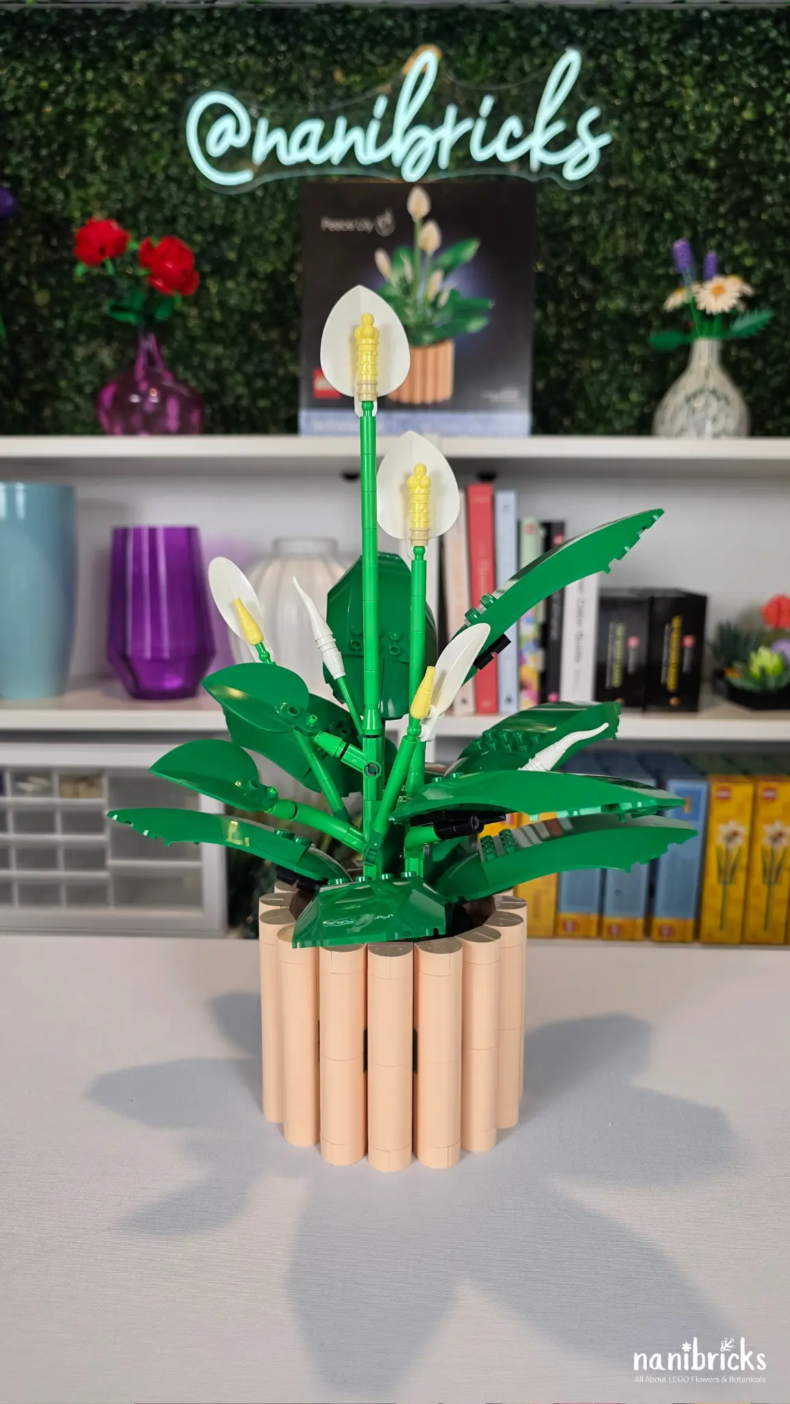 LEGO Botanicals Peace Lily displayed in a textured peach pot with layered green leaves and white blooms.