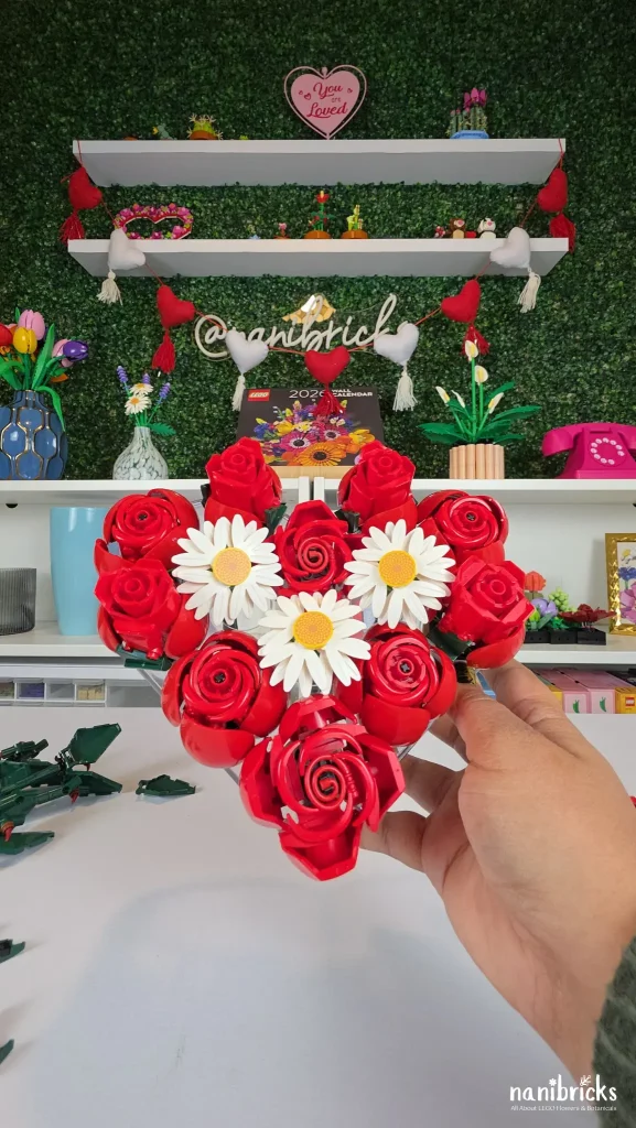 Final LEGO rose arrangement in a heart-shaped vase with daisies and white filler flowers.