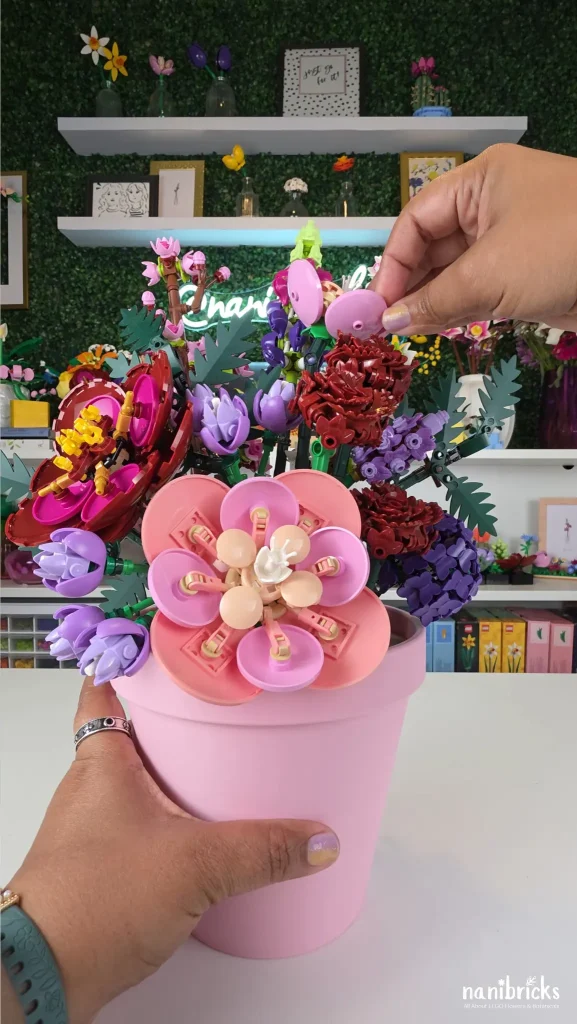 Making final adjustments to balance a custom LEGO flower arrangement in a pink flower pot