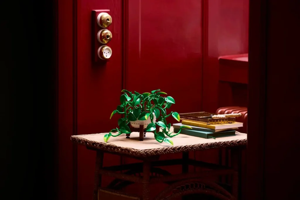 LEGO Botanicals Hanging Golden Pothos (11512) displayed on a small table beside books in a richly decorated room.