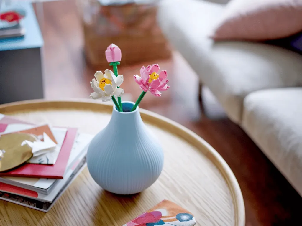 LEGO Lotus Flowers (40647) displayed in a small blue vase on a coffee table.