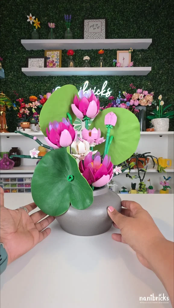Finished LEGO Water Lily Pond flower arrangement with pink water lilies, lotus flowers, orchid branches, and oversized lily pads in a gray vase